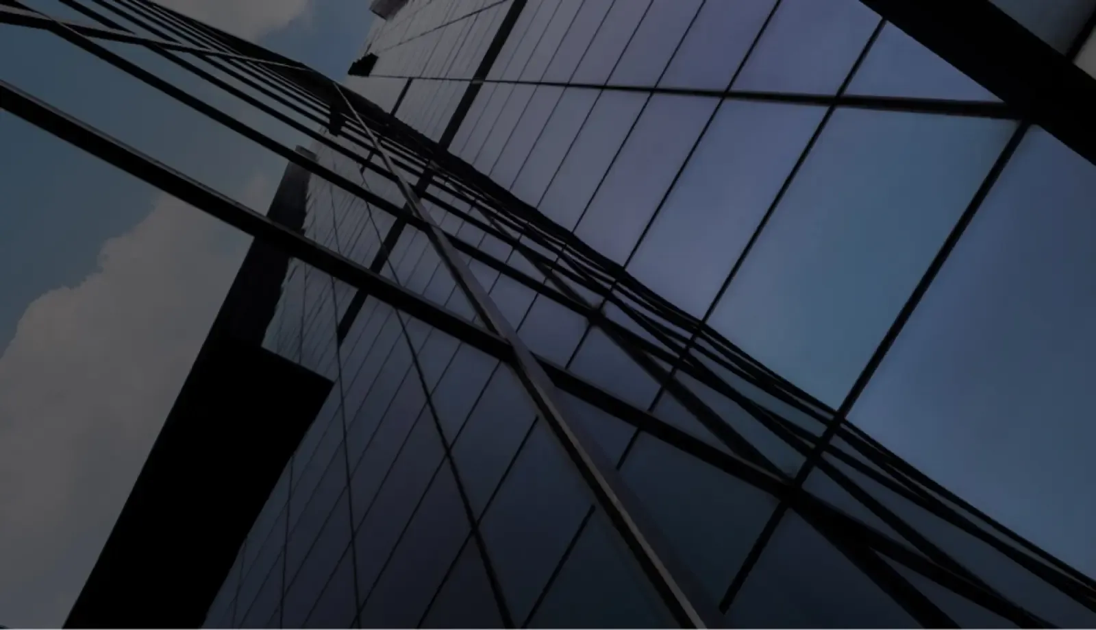 Upward view of a glass office tower against a blue sky