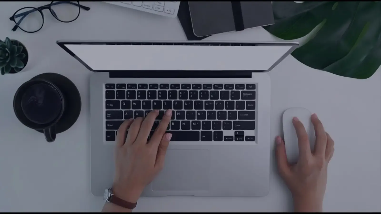 Overhead view of hands typing on a laptop at a tidy desk