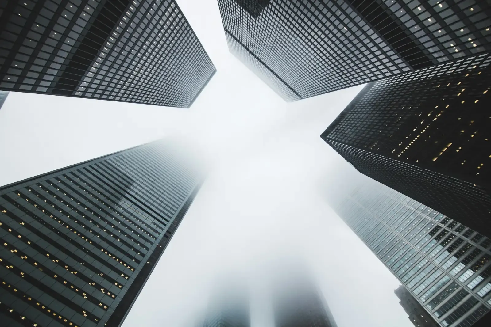 Looking up at high-rise office towers fading into fog